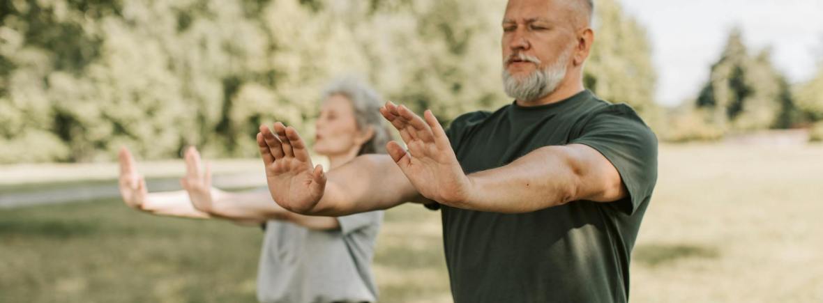 an elderly couple doing yoga with their arms outstretched